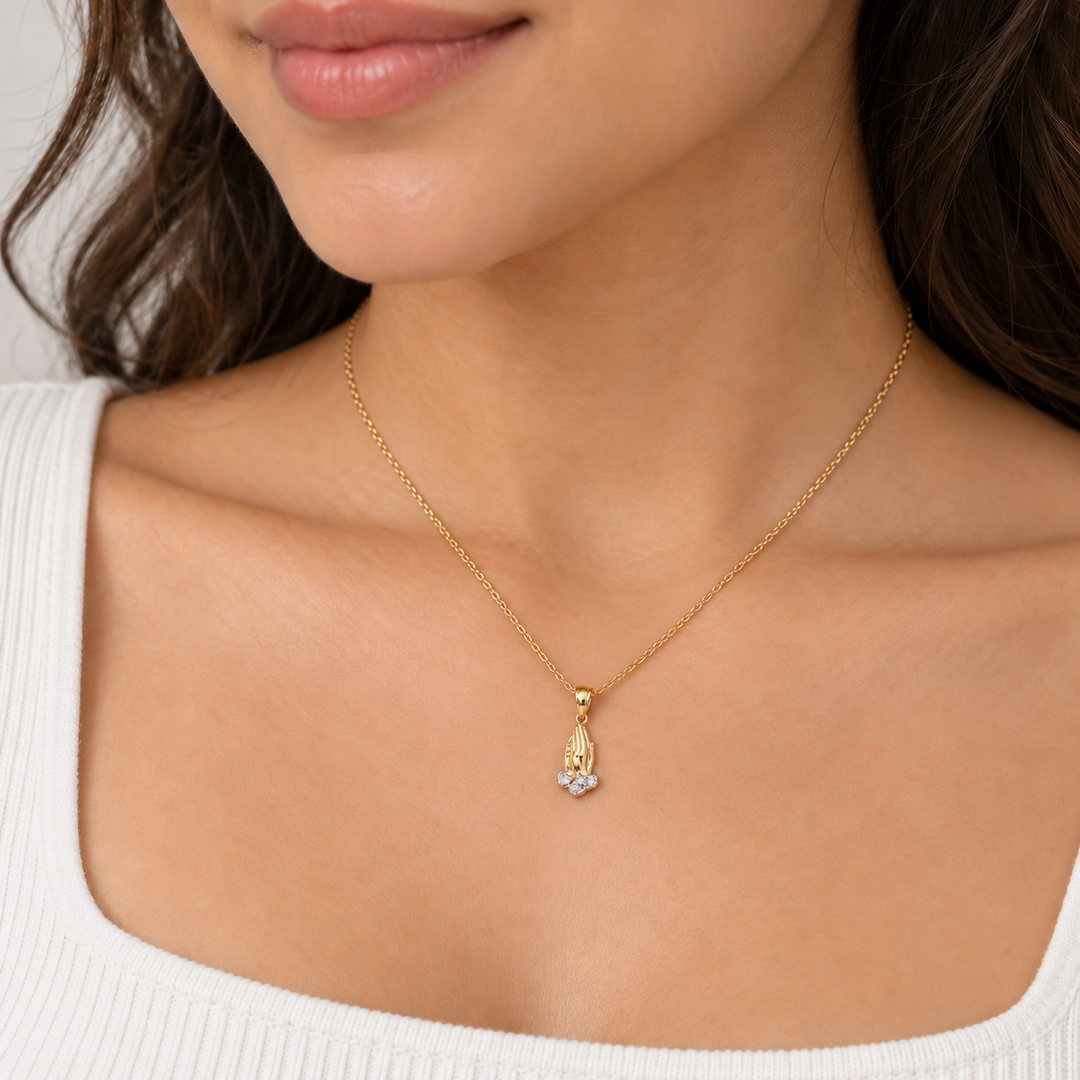 14K yellow gold praying hands pendant with white CZ stones worn on a necklace